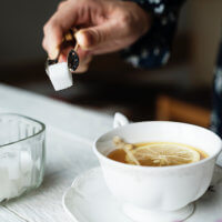 A woman adds sugar cubes to her tea, instead of choosing sorbitol.