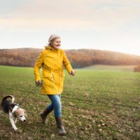 This woman walking her dog outdoors is enjoying the health benefits of green space.